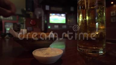 男子在<strong>足球比赛</strong>电视<strong>背景</strong>的体育酒吧喝啤酒吃小吃